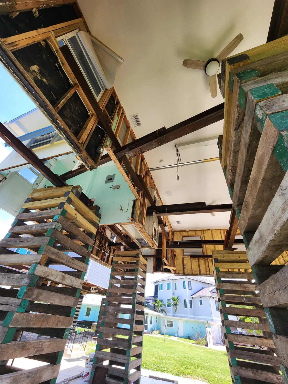 View from beneath a lifted home showing the steel beam frame and cribbing towers carrying the load